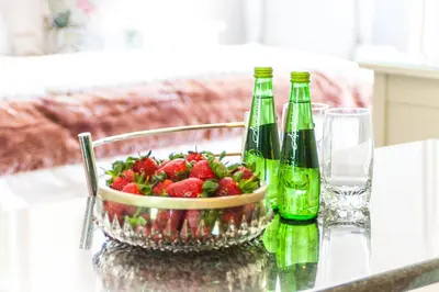 a bowl of strawberries sitting on a table with two bottles at Evertsdal Guesthouse in Durbanville