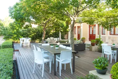 a wooden deck with a table and white chairs at Evertsdal Guesthouse in Durbanville