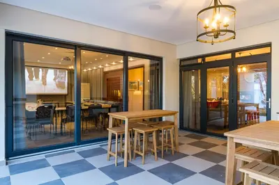 a dining room with glass doors and tables at Evertsdal Guesthouse in Durbanville