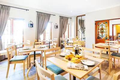 a dining room with wooden tables and chairs at Evertsdal Guesthouse in Durbanville