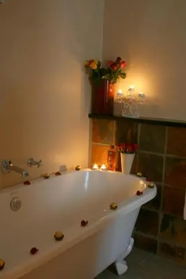 a bath tub in a bathroom with candles and flowers at Evertsdal Guesthouse in Durbanville