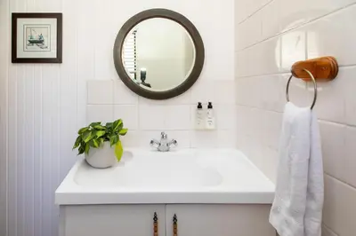 a white bathroom with a sink and a mirror at Loddey's Guesthouse by Beach Collection Winelands in Strand