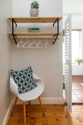 a white chair with a pillow on it in a room at Loddey's Guesthouse by Beach Collection Winelands in Strand