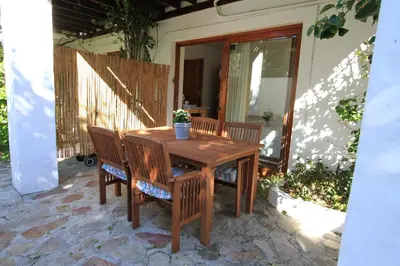 a wooden table and chairs on a patio at Haven of Peace and Garden Cottage in Hermanus