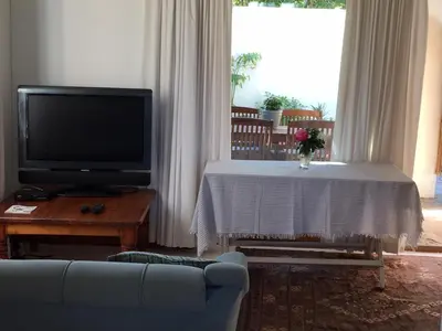 a living room with a tv and a couch and a table at Haven of Peace and Garden Cottage in Hermanus