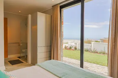 a bedroom with a large glass door leading to a bathroom at The View, Apartment, with magnificent sea view in Hermanus
