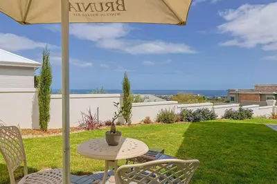 a table and chairs under an umbrella on a lawn at The View, Studio in Hermanus