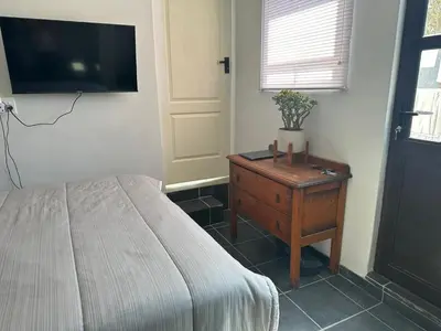 a bedroom with a bed and a dresser and a tv at Ruach 5 in Cape Town