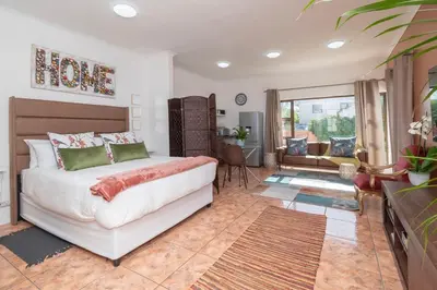 a bedroom with a bed and a living room at Apartment in Milnerton close to Woodbridge Island in Cape Town