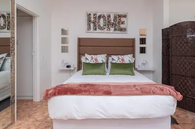 a bedroom with a large bed with two green pillows at Apartment in Milnerton close to Woodbridge Island in Cape Town