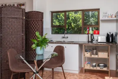 a kitchen with a glass table and chairs at Apartment in Milnerton close to Woodbridge Island in Cape Town