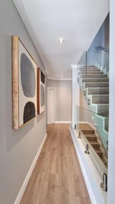 a hallway with stairs and paintings on the wall at Pearl Valley Golf Lodge - loadshedding free in Simondium