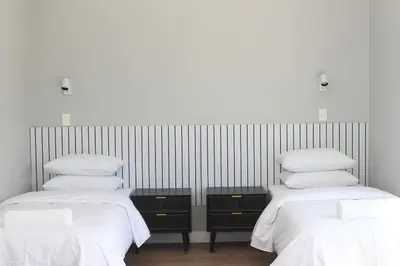 two beds in a room with white sheets and pillows at Pearl Valley Golf Lodge - loadshedding free in Simondium