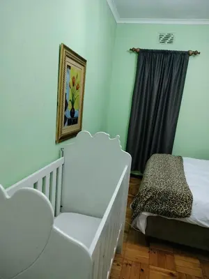 a bedroom with a crib and a bed and a window at Near Grandwest in Cape Town