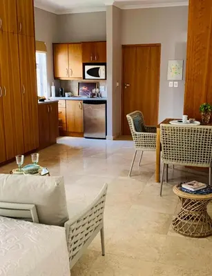a living room with a table and chairs and a kitchen at Villa Georgia in Cape Town