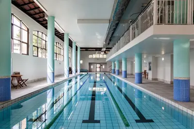 a large swimming pool in a building with blue columns at Island Club Hotel & Apartments in Cape Town