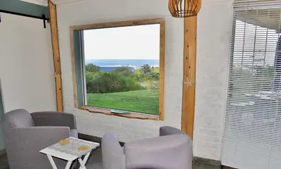 a room with chairs and a window with a view at Seaview on 2822 Happy Whale Cottage in Bettyʼs Bay