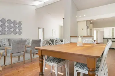 a dining room with a wooden table and chairs at Voelklip Beach Cottage in Hermanus