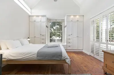 a white bedroom with a large bed and windows at Voelklip Beach Cottage in Hermanus