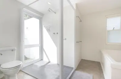 a white bathroom with a toilet and a shower at Voelklip Beach Cottage in Hermanus