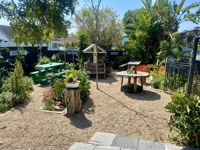 a garden with a table and benches and plants at Suzies Huis Restaurant Bed and Breakfast in Cape Town