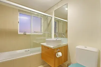 a bathroom with a sink and a toilet and a mirror at Horizon Bay 1201 in Bloubergstrand