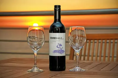 a bottle of wine and two wine glasses on a table at Horizon Bay 1201 in Bloubergstrand