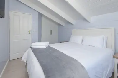 a white bedroom with a white bed and a white door at The Blue Cabin in Fisherhaven