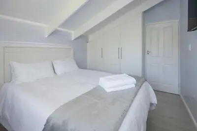 a white bed in a white room with a white door at The Blue Cabin in Fisherhaven