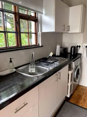 a kitchen with a sink and a stove at Milner Cottage: Digital Nomad Oasis in Cape Town