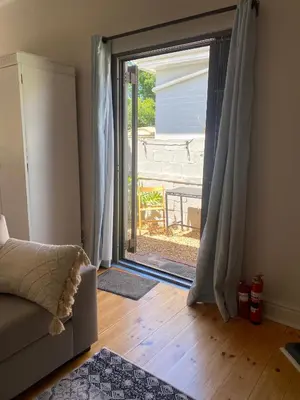 a living room with a door open to a patio at Milner Cottage: Digital Nomad Oasis in Cape Town