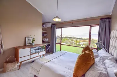 a bedroom with a bed and a large window at Pearlmar Views in Cape Town