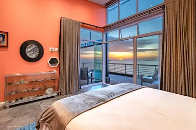a bedroom with a bed and a large window at Serviced Beach Penthouse, 100k Gemstone display, All Ensuite in Cape Town