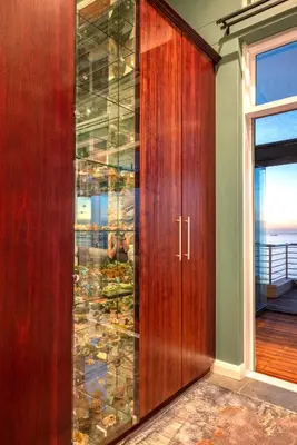 a wooden cabinet with glass doors in a room with a window at Serviced Beach Penthouse, 100k Gemstone display, All Ensuite in Cape Town