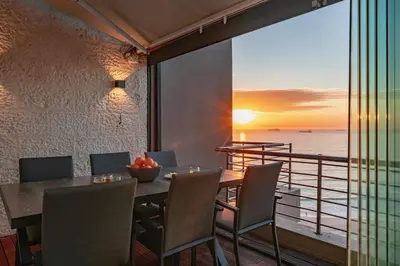 a dining room with a table and a view of the ocean at Serviced Beach Penthouse, 100k Gemstone display, All Ensuite in Cape Town
