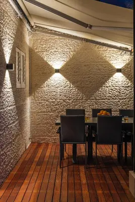 a dining room with a table and chairs and a brick wall at Serviced Beach Penthouse, 100k Gemstone display, All Ensuite in Cape Town