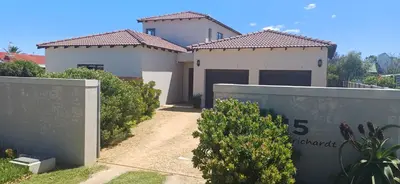 a house with two garage doors and a fence at La Haven Self Catering in Hermanus