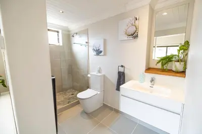 a bathroom with a toilet and a sink and a mirror at La Haven Self Catering in Hermanus