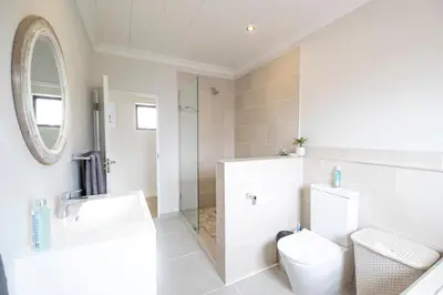 a bathroom with a toilet and a sink and a mirror at La Haven Self Catering in Hermanus
