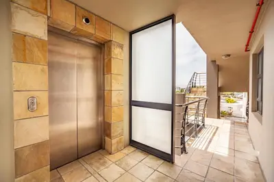a pivot door in a house with a balcony at Beachfront 3rd floor 2 bedroom w communal swimming pool- B16 Blouberg in Bloubergstrand