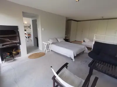 a bedroom with a bed and a chair and a fireplace at Betty's Bay Cottage in Bettyʼs Bay