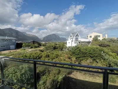 a view of houses and mountains from a balcony at Betty's Bay Cottage in Bettyʼs Bay