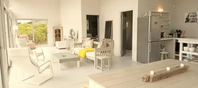 a living room with white furniture and a kitchen at Betty's Bay Cottage in Bettyʼs Bay