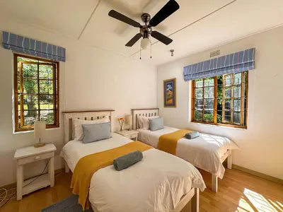 a bedroom with two beds and a ceiling fan at Arkelshoek Cottages in Stellenbosch