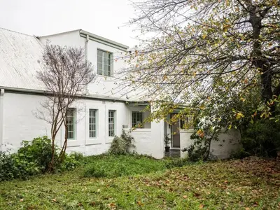 a white house with a tree in front of it at Arkelshoek Cottages in Stellenbosch