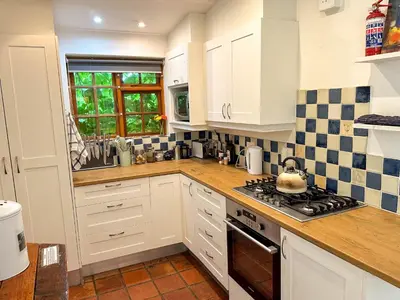 a kitchen with white cabinets and a stove top oven at Arkelshoek Cottages in Stellenbosch