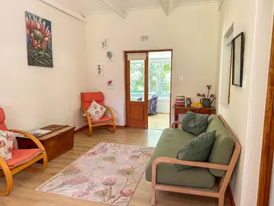 a living room with a green couch and chairs at Arkelshoek Cottages in Stellenbosch
