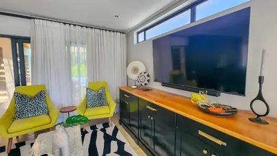 a living room with a large television and two yellow chairs at House of Anjel in Suider-Paarl