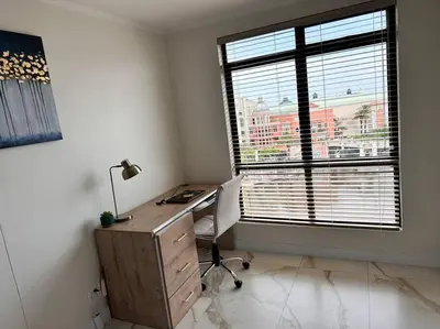 an office with a desk and a large window at 30% off Designer Penthouse - backup power - Cape Town in Cape Town