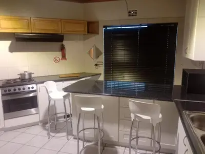 a kitchen with white chairs and a counter top at Cape Town 5 bedroom house Belhar in Cape Town